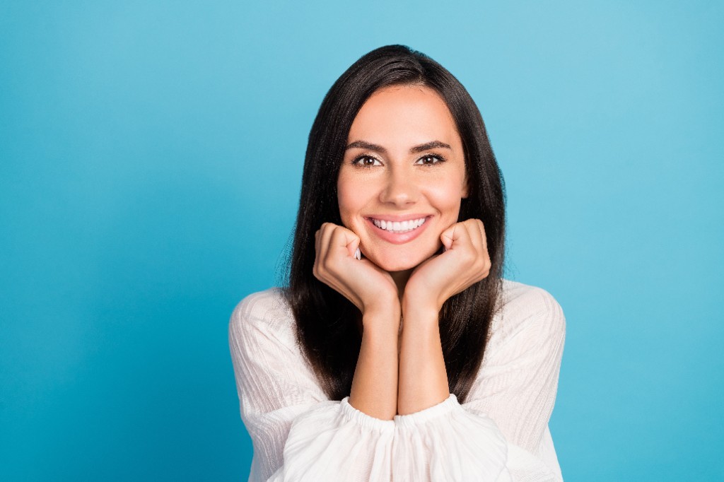 Smiling patient with bright skin against a blue background