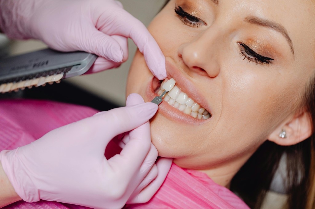 Dentist checking a patient's tooth shade during teeth whitening treatment